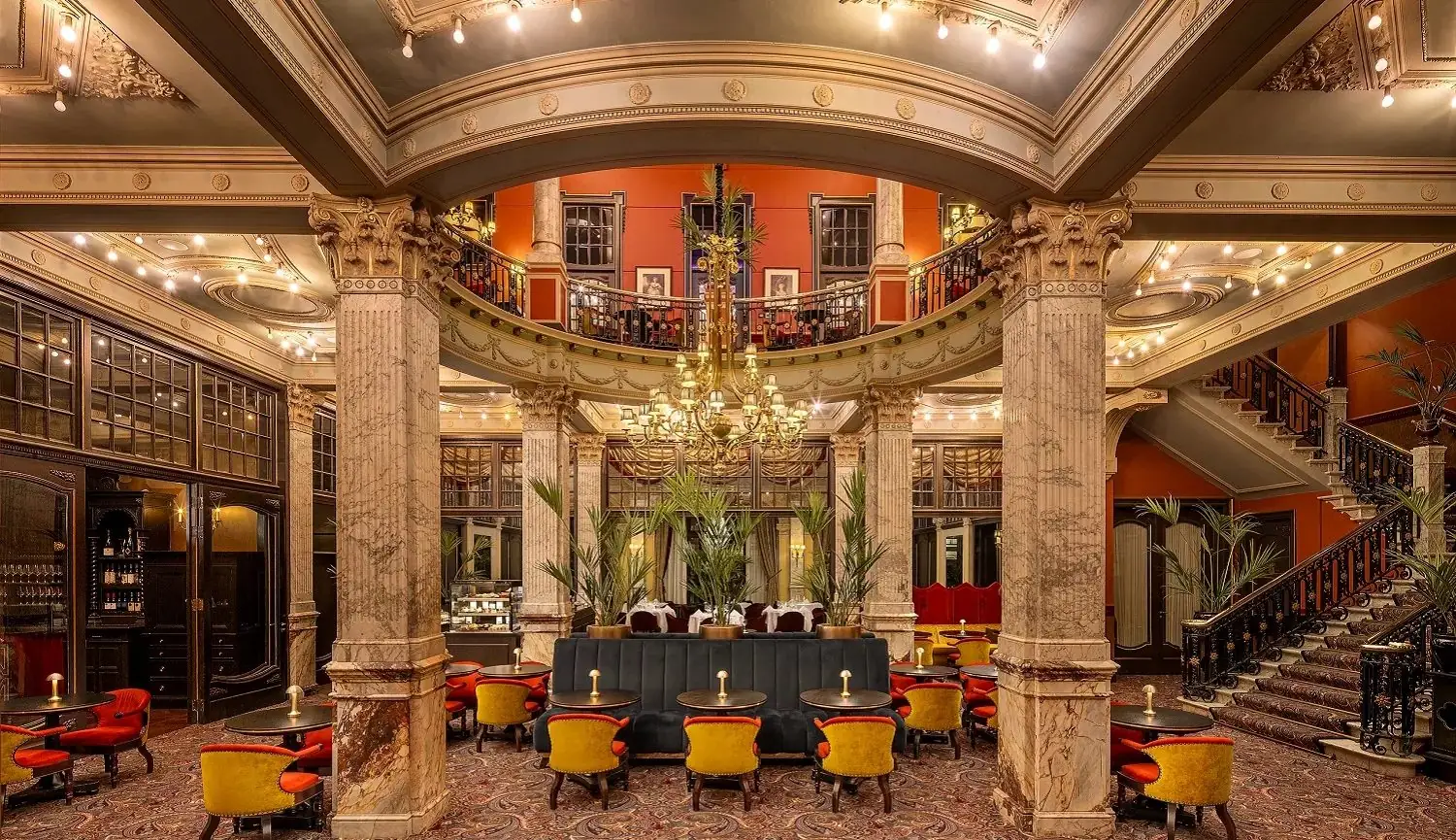 Hotellobby met kroonluchter, plafondspots en messing tafellampen in warm licht