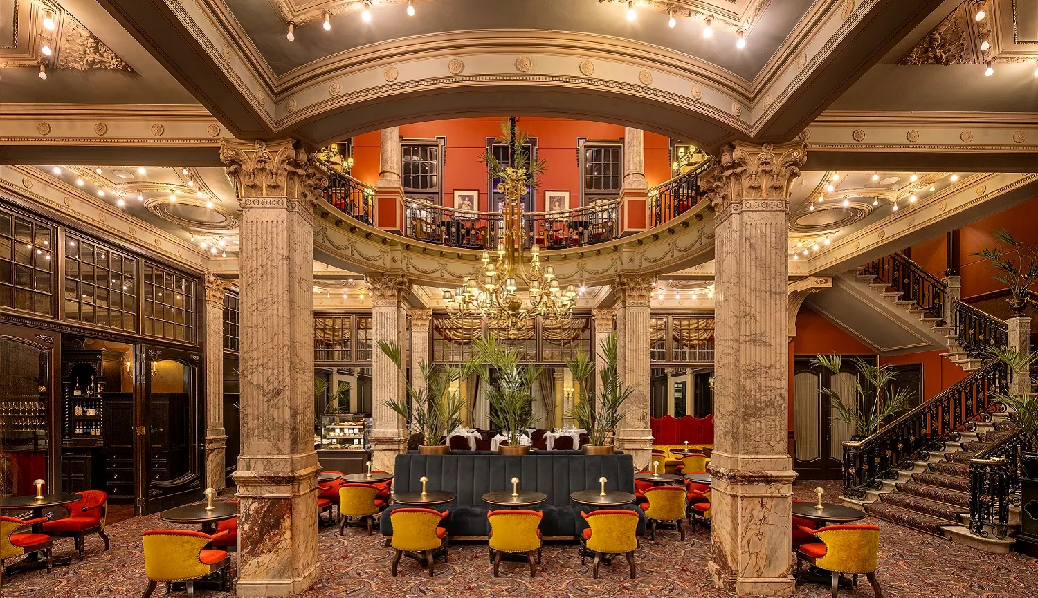 Hotellobby met warm, gelaagd licht en monumentale hanglampen